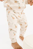 A baby wearing a matching cream-colored two-piece outfit with a light brown duck and green leaf pattern, shown from the waist down on a white background.