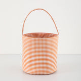 Orange and white gingham  bucket bag with a handle on a light gray background