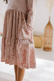 Pink velvet long sleeve dress with pockets, worn by a person, with a blurred indoor background