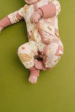 Baby in a patterned outfit on a green background