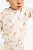 Child wearing a long-sleeve shirt with duck pattern on a white background