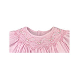 Close-up of a pink dress with intricate smock detailing on a white background