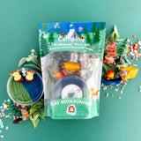 Camping-themed kiddough play kit with toys and packaging on a green background