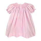 Pink dress with smocked neckline and puff sleeves and buttons down the back on a white background 