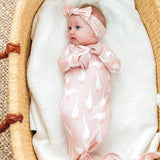 Baby in a pink goose print gown  with a bow in a moses basket