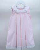 A light pink sleeveless dress with white lace trim on the collar and hem, hanging on a white wooden hanger against a light gray background.