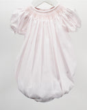 A light pink baby smocked romper with short puff sleeves and a gathered, balloon-like silhouette, hanging on a white hanger against a light gray background.