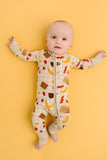 Baby wearing a onesie with breakfast food-themed print on a yellow background