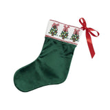 A dark green velvet Christmas stocking with a white cuff decorated with three embroidered Christmas trees and red bows, finished with a red ribbon bow on the side.