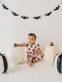 Baby in a black cat Halloween-themed outfit with pumpkins and bat decorations on a white background