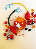 Children's toys including a fire truck, firefighter helmet, and red fire hydrant on a beige background.