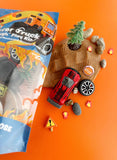 Toy truck and accessories on an orange background with packaging to the side.